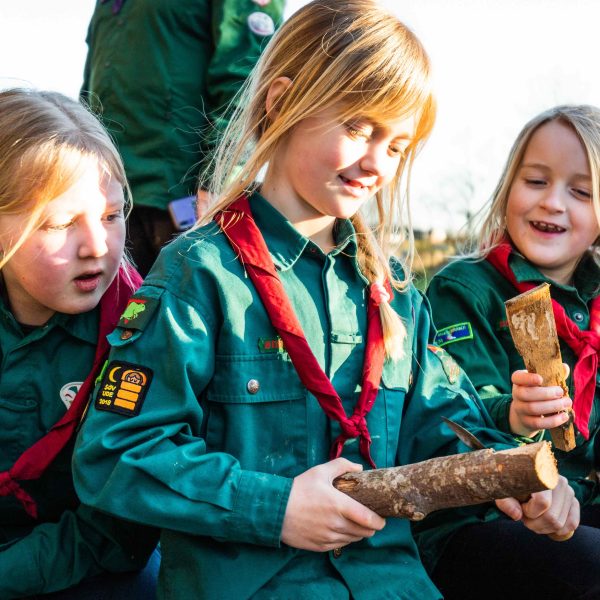 To spejderledere viser en færdselstavle for en gruppe børn