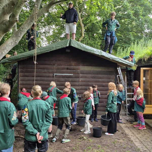 To spejderledere viser en færdselstavle for en gruppe børn